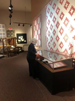 Carol Dunn, Executive Director, Wayne County Historical Society, inspects part of the new exhibit, Threads of Our Lives, at the Main Museum. The exhibit, and another new exhibit, History of Wayne County’s Independent Pharmacies, will be open to the open to the public, Saturday May 22. The Open House is from 11 a.m. to 4 p.m. and features free admission that day.